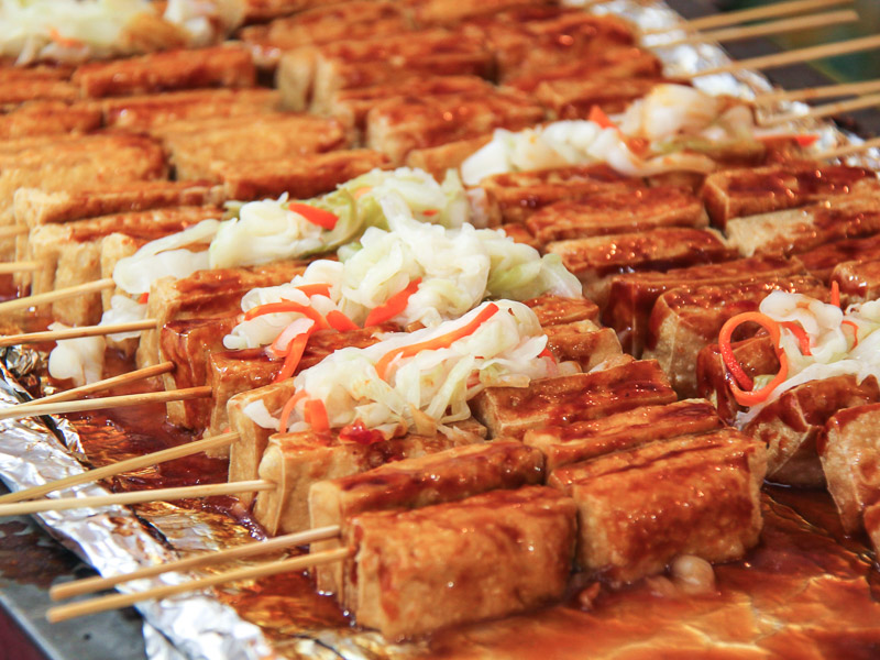 Many sticks of stinky tofu on a tray wrapped with aluminum foil