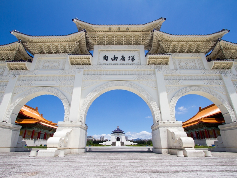 Looking through a white gate at a large square and white and blue monument to Chiang Kai Shek in Taipei