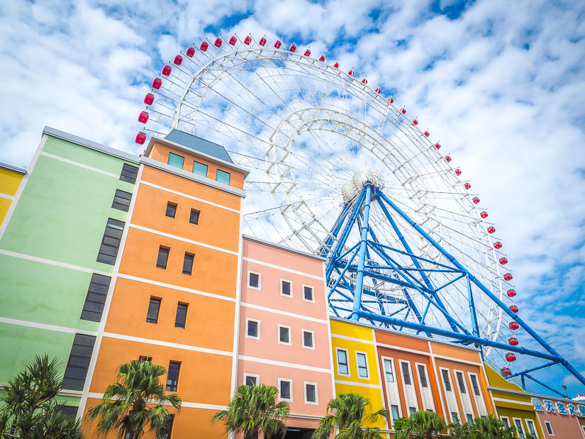 A tall Ferris wheel rising above a colorful outlet mall in Taichung