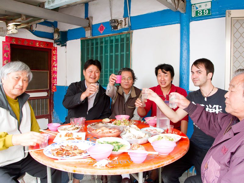Nick Kembel sitting with a group of taiwanese men and doing cheers with glasses of beer