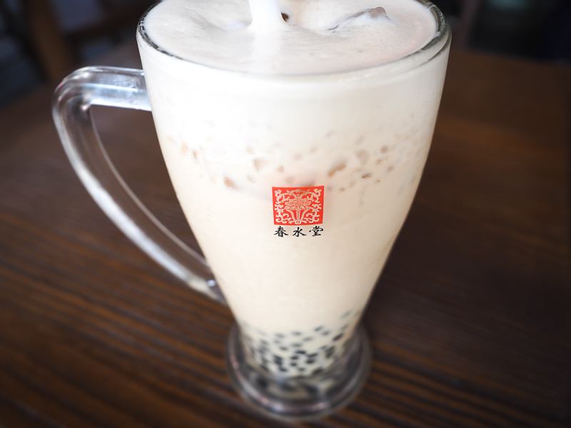 Close up of a glass mug of pearl milk tea with bubbles on the bottom and foam on the top