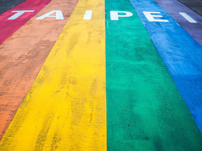 A pride flag painted on the road with the word Taipei in white at the top