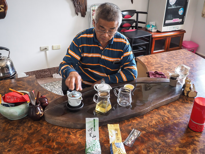 A elderly male Taiwanese tea farmer carefully making tea using traditional tea brewing equipment