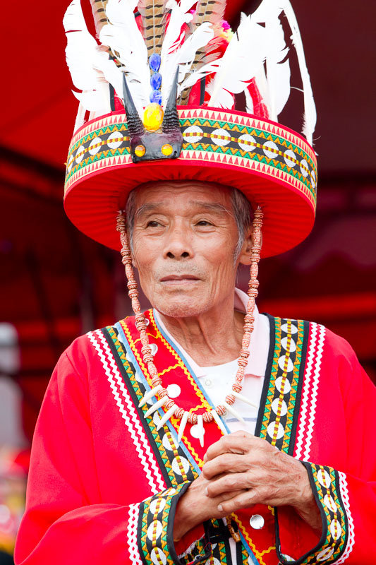 Portrait of an elderly Taiwanese aboriginal man in traditional costume with a large round hatg with feathers