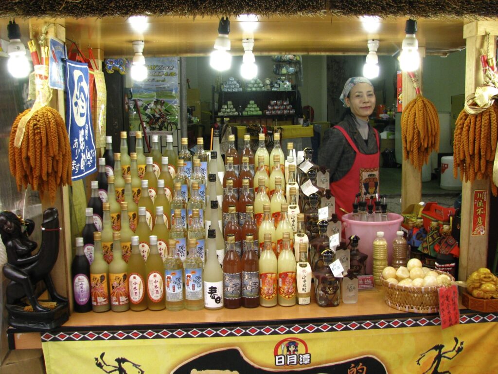 A vendor with many bottles of aboriginal millet wine and woman standing behind the stall