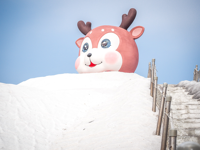 A staircase leading up a mountain of salt, with a blown up deer head statue at the top