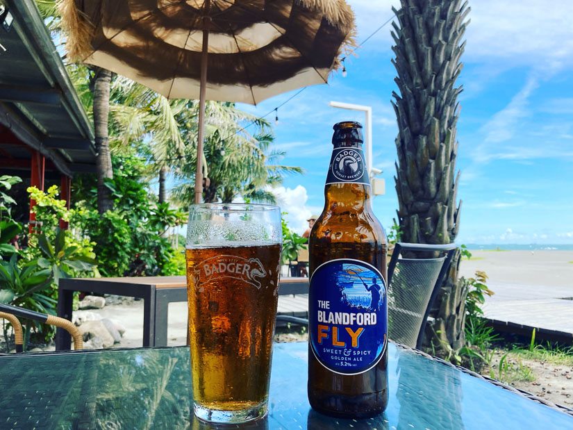A bottle and pint of beer on the table in a beach bar