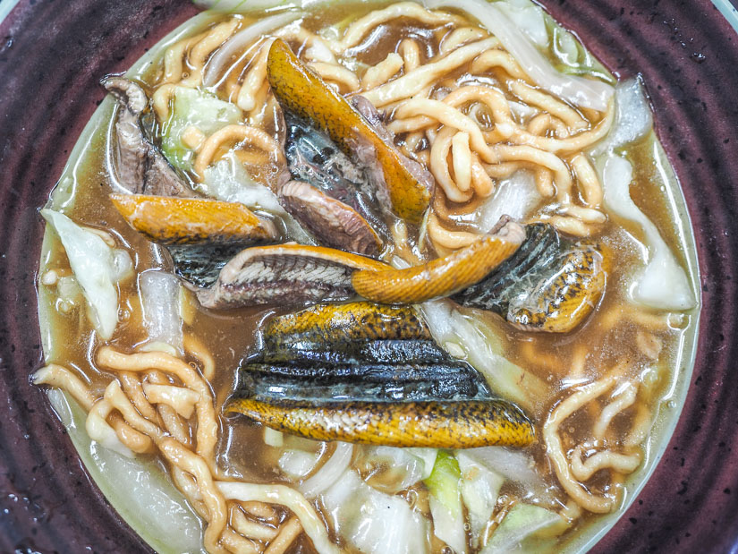 Looking down at a bowl of noodles with slices of eel