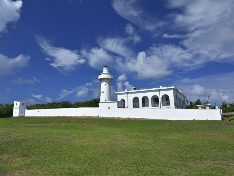 A white lighthouse building on a grassy hill