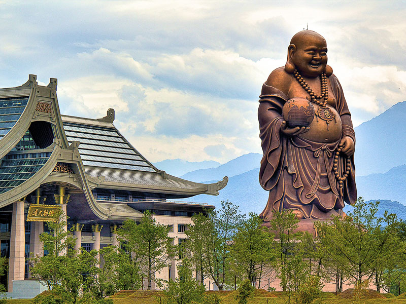 A giant bronze Buddha statue in front of a temple at Emei in Hsinchu