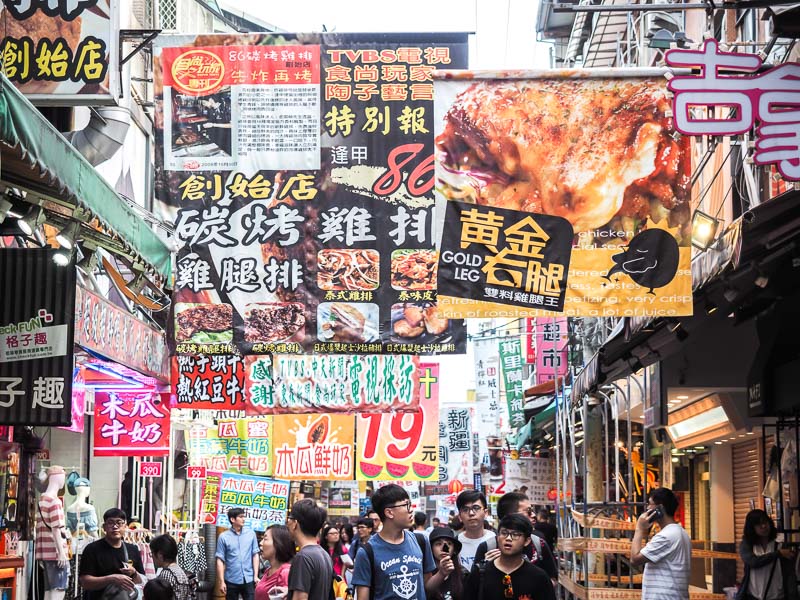Many food signs above shoppers in Taichung's Fengchia Night Market