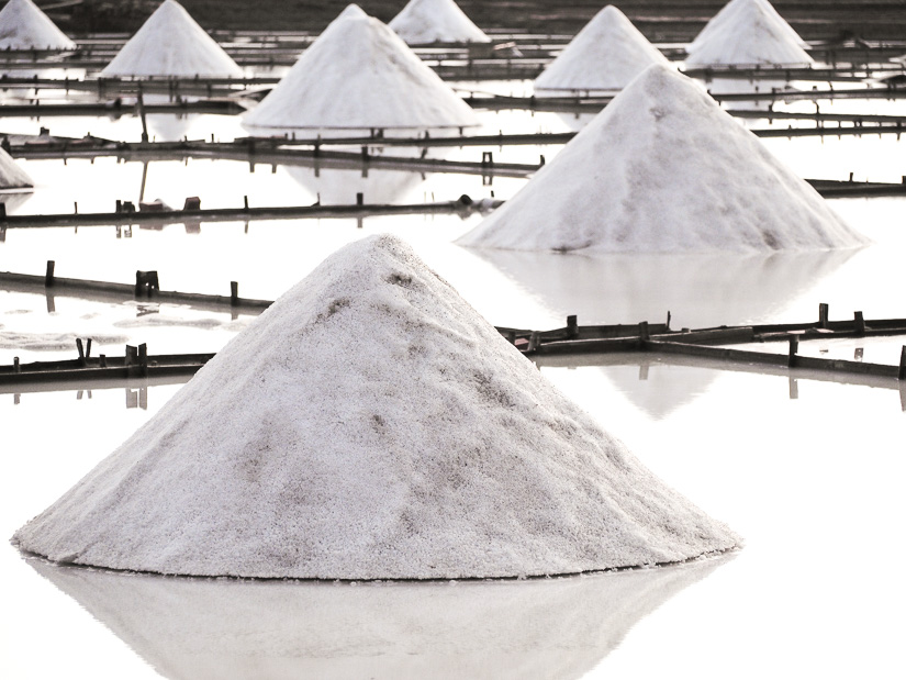 Some pyramid-shaped mounds of salt in water water fields