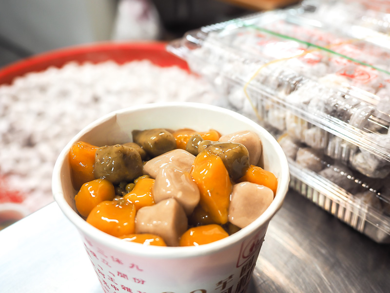 A white paper bowl filled with taro and sweet potato balls
