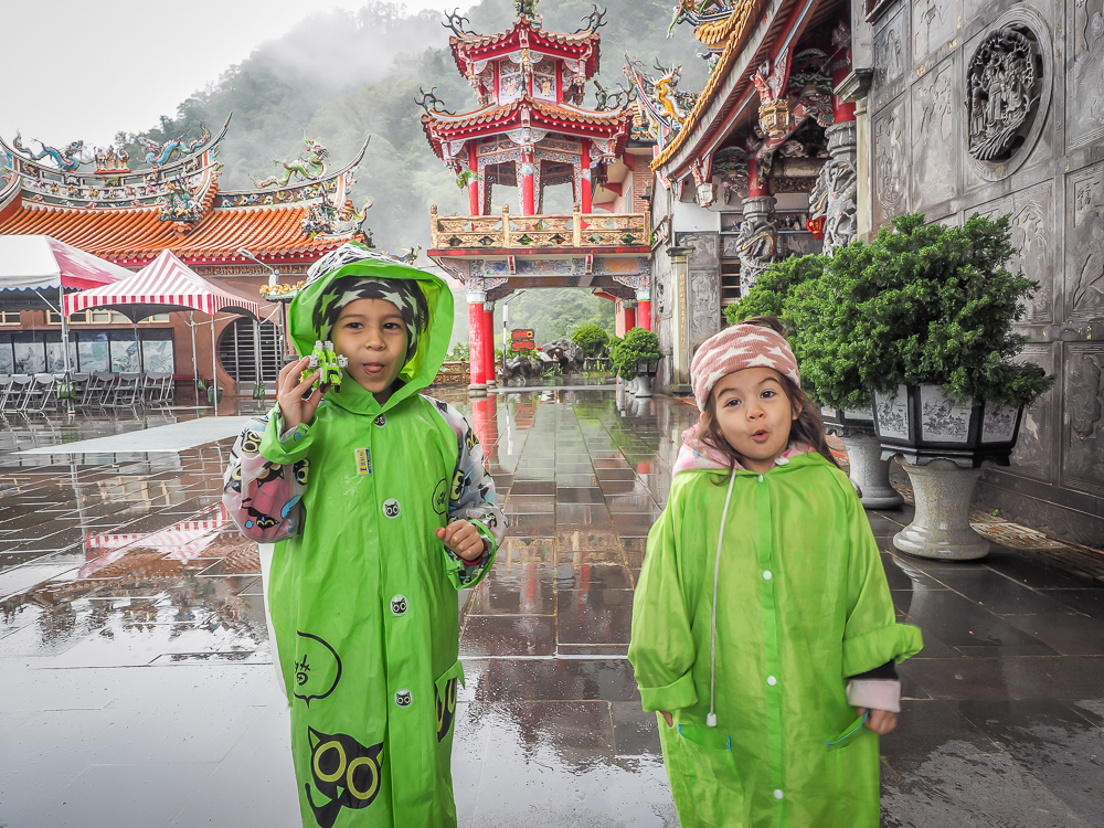 Two kids wearing green rain jackets at a temple in Taiwan