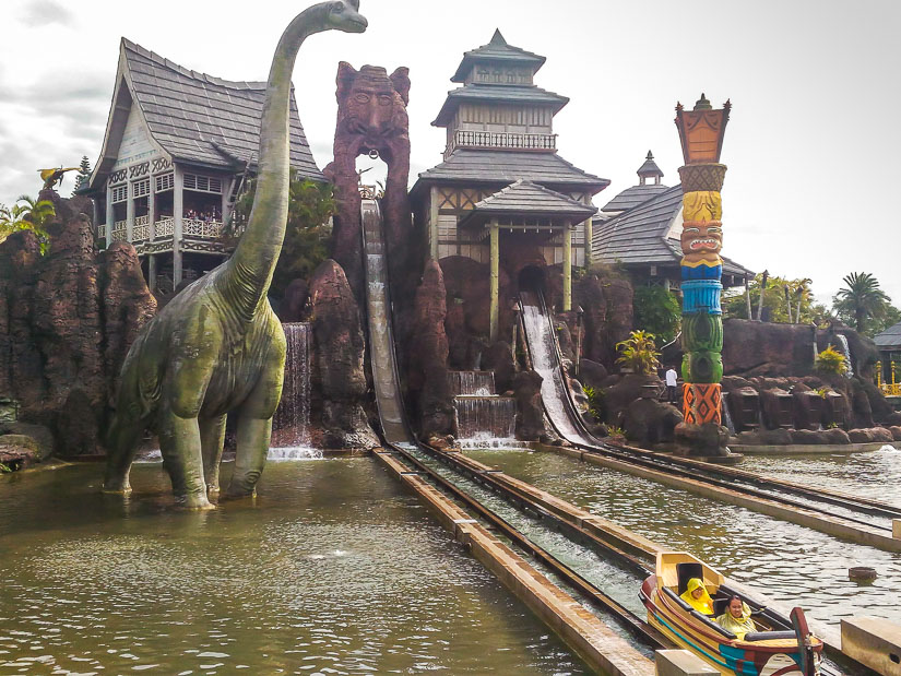 Two kids going down a water ride with giant dinosaur at Leofoo Village Amusement Park