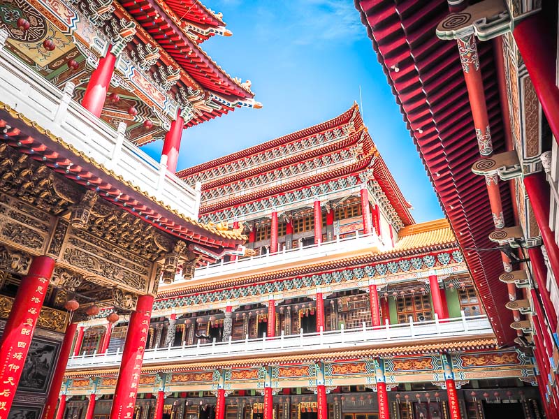 Looking up from the courtyard of a huge red temple, with temple halls on every side