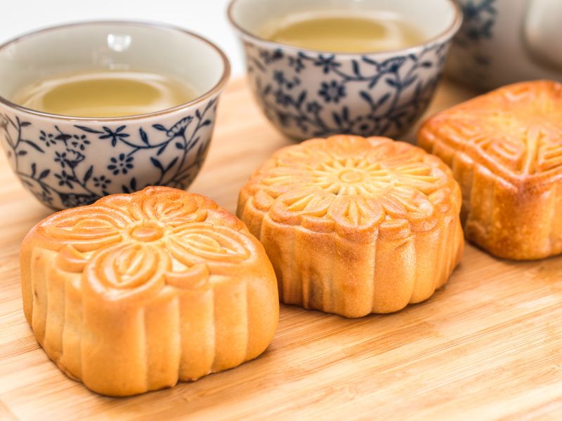 Close up of two Taiwanese moon cakes in front of two glasses of tea