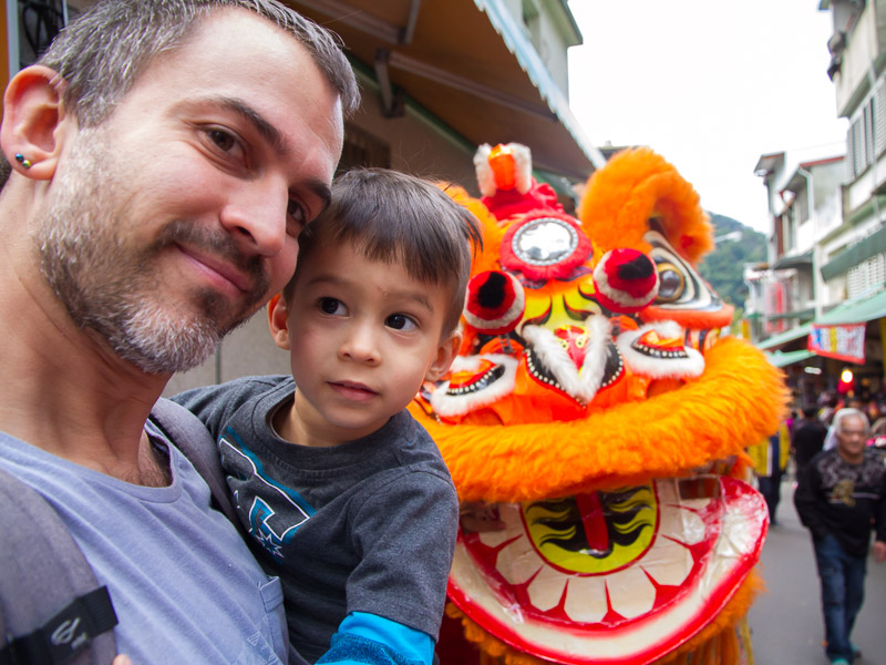 Nick Kembel holding his son with a traditional Taiwanese lion behind them during Lunar New Year festivities