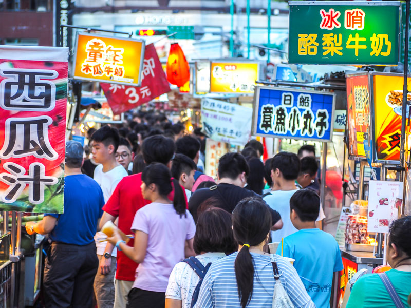 Crowds of market-goers walking between food stalls at Ningxia Night Market