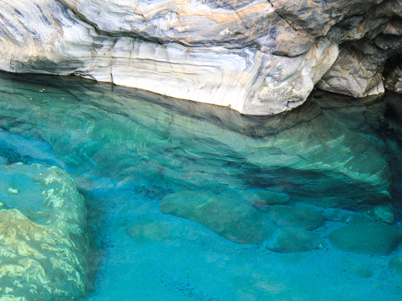 Looking into a pool of very clear blue water with rocks