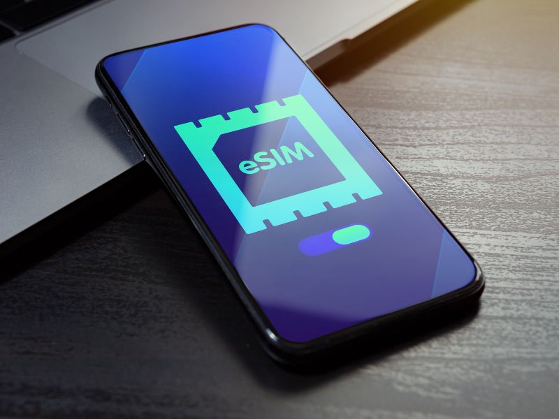 A mobile phone that has a light blue eSIM symbol on a dark blue screen.
