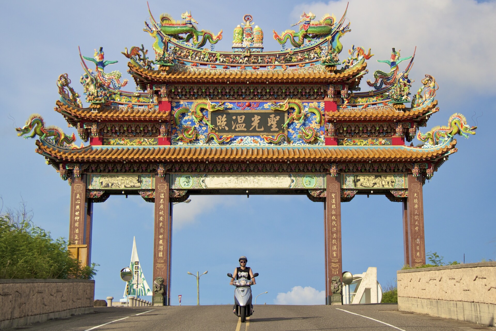 Nick Kembel riding a scooter under a traditional gate in Taiwan