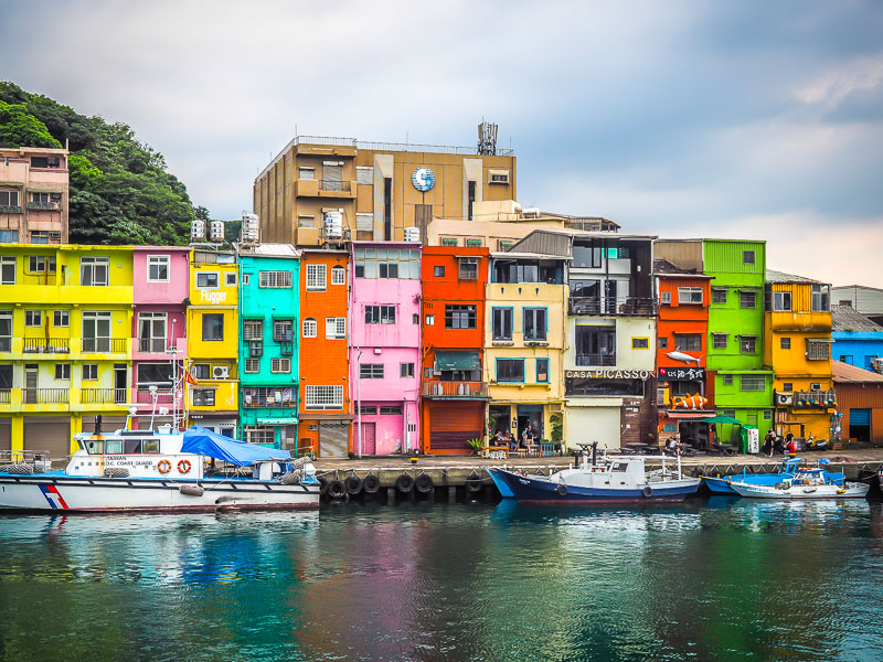 A row of colorfully painted houses facing a fishing harbor