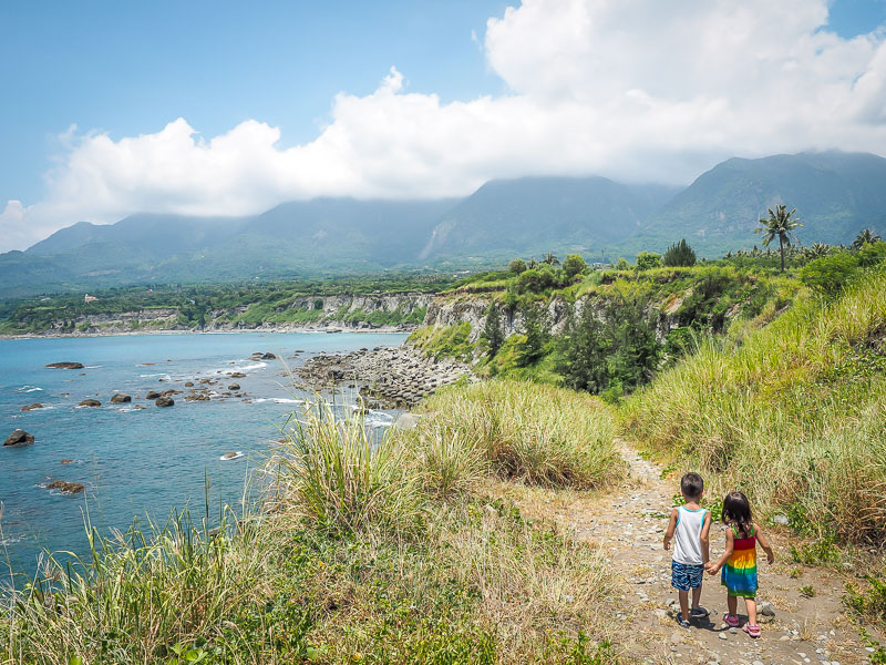 Two kids walking on a path along the coast of Taitung with mountains in the background