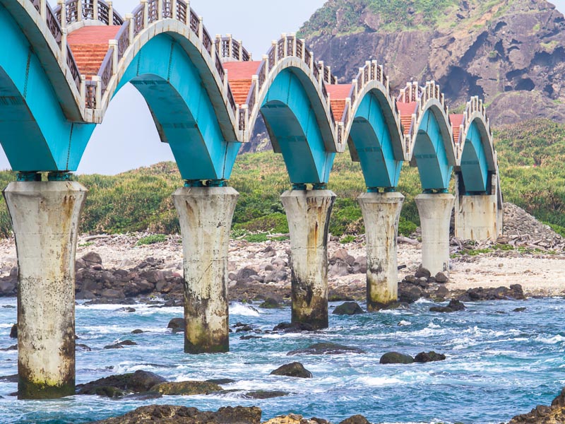 A bridge with multiple arches leading from the coast to a small island