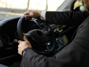 Close up of a driver's arms while holding the steering wheel on a private transfer from the airport to the city