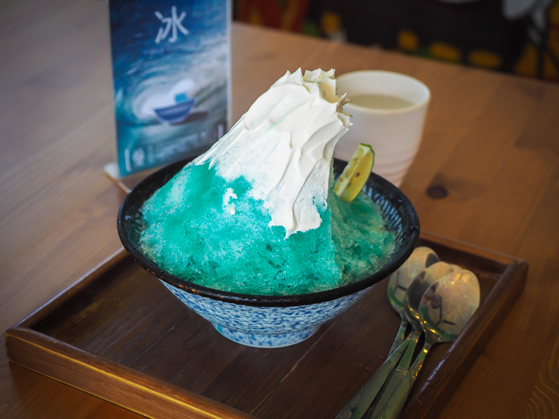 A bowl of shaved ice shaped like a blue wave with white top