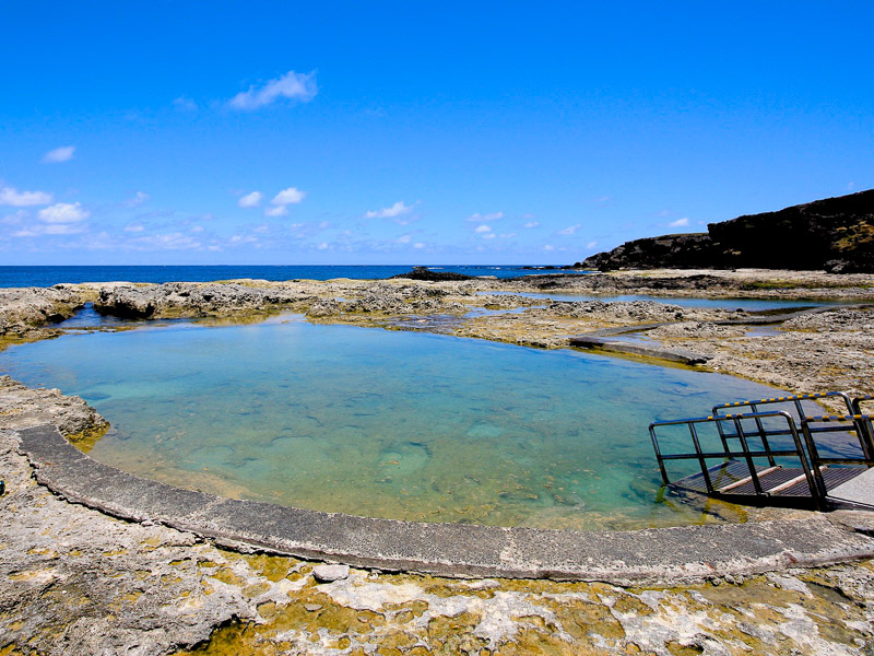 A round hot spring pool on the coast with walking ramp down into it